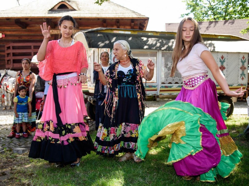 Romani women dance in brightly coloured traditional clothing