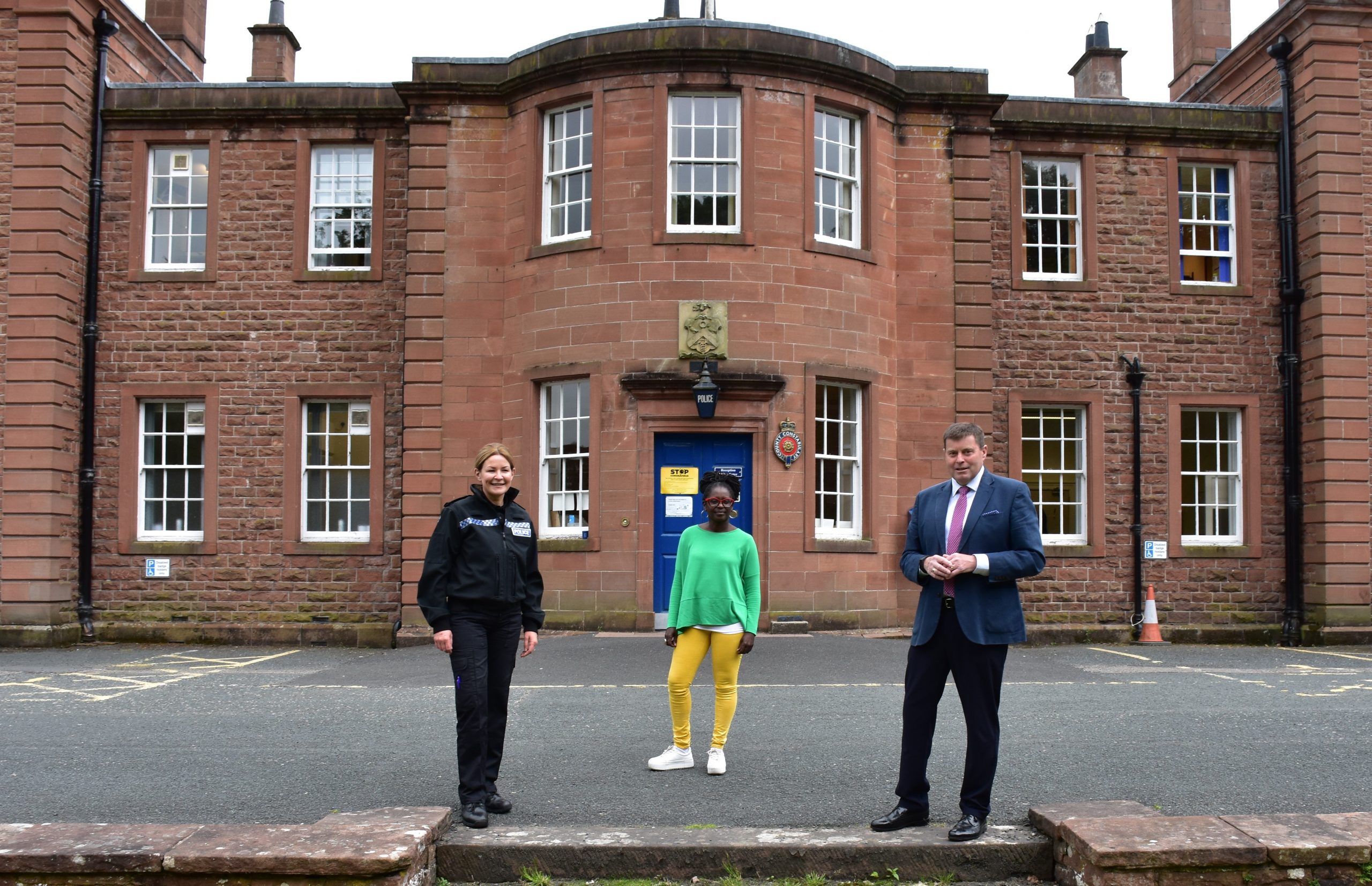 CS Sarah Jackson, Janett Walker and PCC Peter McCall stand in front of a Cumbria Police building