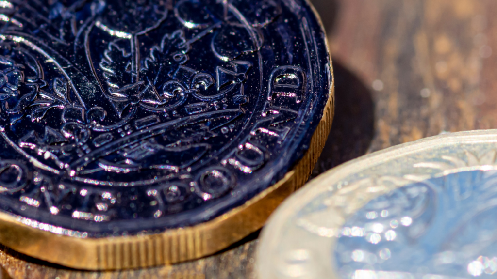 a pile of pound coins with the top one painted a shiny black colour