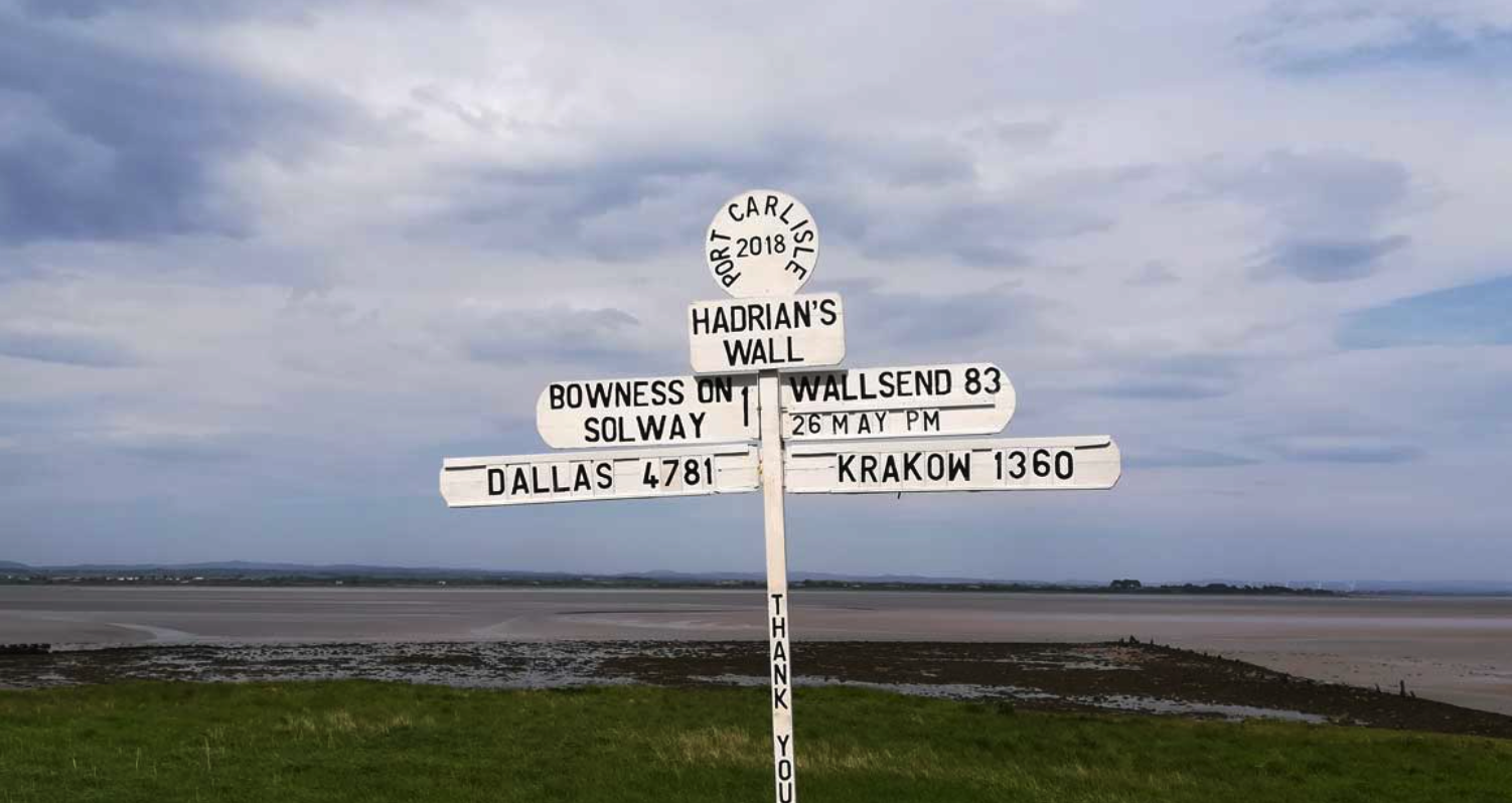 A signpost for Hadrians wall that points to cumbria one side and northumbria on the other side