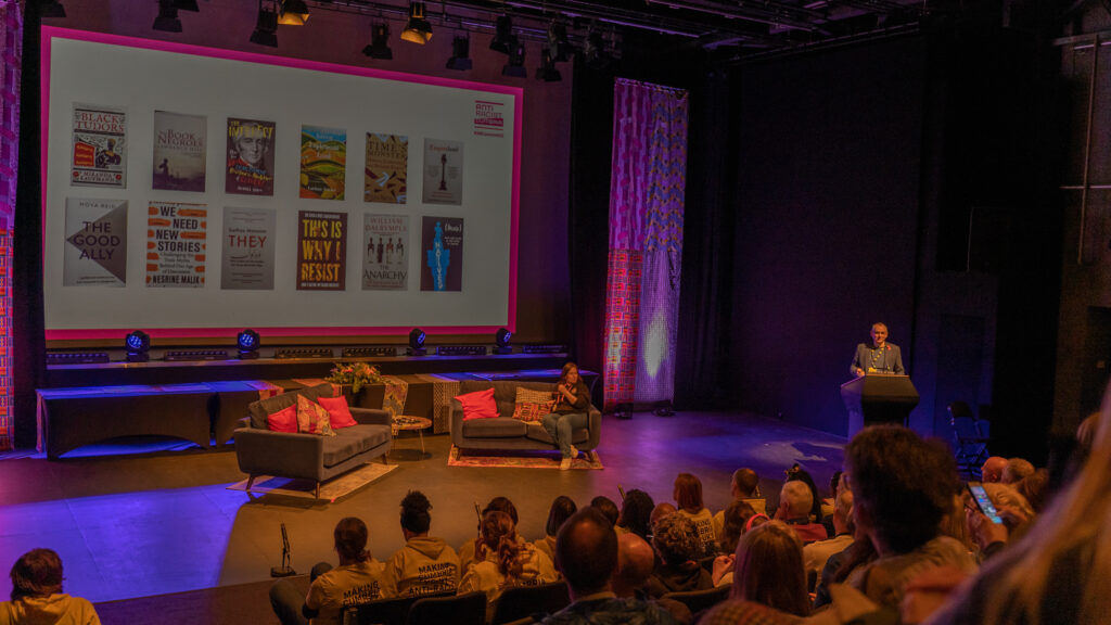 Two sofas are on stage, in the background two banners of a variety of African print fabrics.