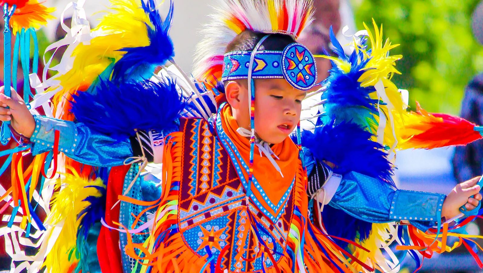 Young Dancer in bright coloured outfit made of many brightly coloured beads, silk and feathers at a Pow Wow dancing competition - Photo by Melissa Largo