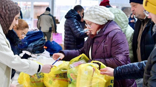 People handing out full yellow carrier bags
