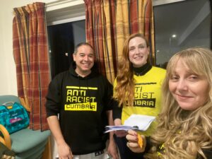 Three of our Anti Racist Cumbria facilitators wearing black and yellow Anti Racist Cumbria hoodies & tees