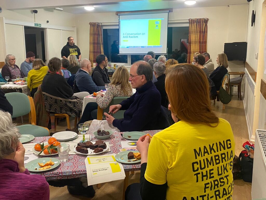 A group of people at tables taking part in an Anti Racist Cumbria event