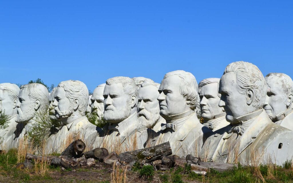 Large statues of male heads in a field. 